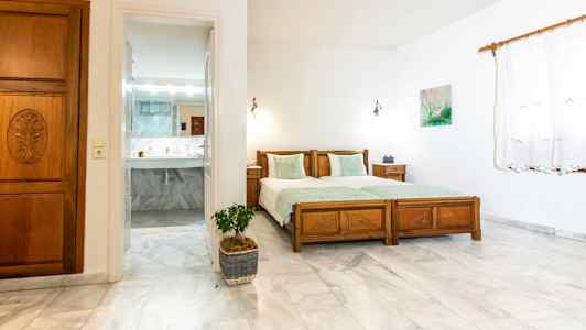 Makuuhuone, jossa kaksi erillistä sänkyä ja ovi johtaa kylpyhuoneeseen. (Tekoälyn luoma teksti)