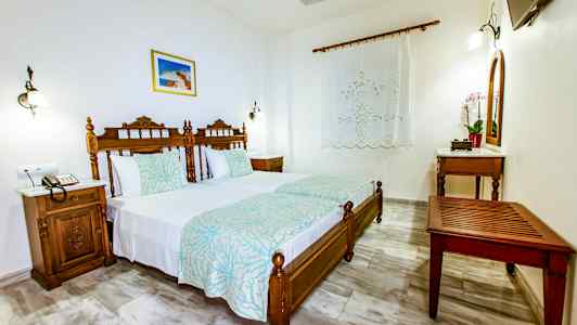 Makuuhuone, jossa on kaksi erillistä vuodetta, puukalusteet ja koristellut sängynpäädyt. (Tekoälyn luoma teksti)