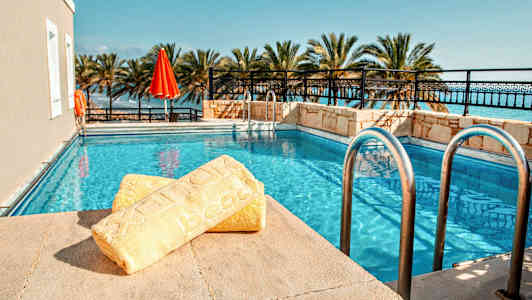 Uima-allas, jota ympäröivät palmupuut, etualalla keltainen pyyhe. (Tekoälyn luoma teksti)