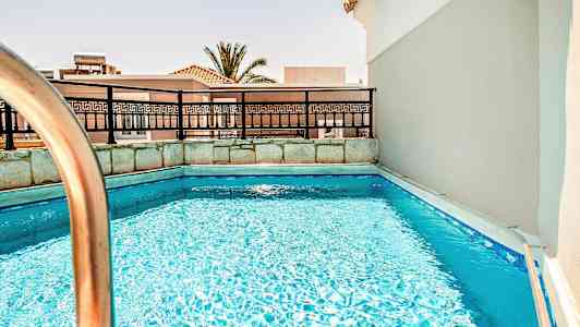 Kuva pienestä uima-altaasta, aidasta ja taustalla näkyvistä rakennuksista. (Tekoälyn luoma teksti)