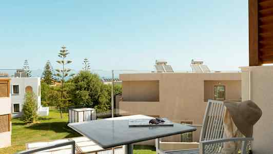 Parveke, jossa ulkokalusteita, näkymä vihreään puutarhaan rakennusten ympäröimänä. (Tekoälyn luoma teksti)