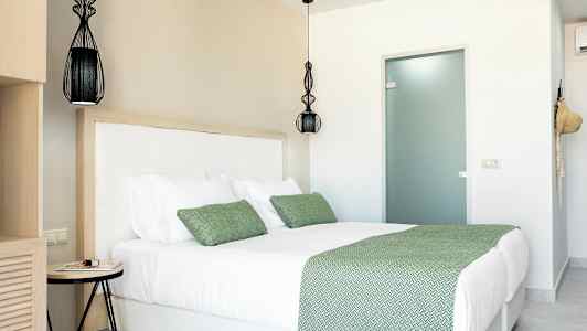 Huone, jossa on parivuode, vihreät vuodevaatteet ja tyynyt. (Tekoälyn luoma teksti)