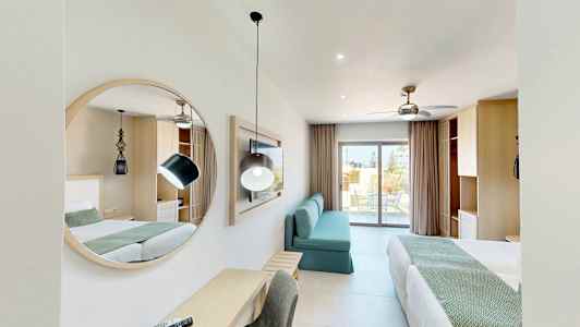 Moderneissa hotellihuoneessa on kaksi sänkyä, peili, sohva ja kirjoituspöytä. Taustalla näkyy parveke. (Tekoälyn luoma teksti)