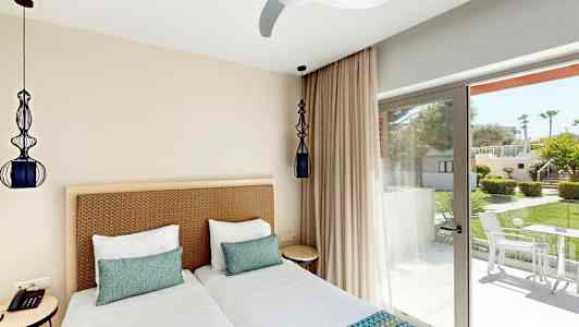 Hotellihuone, jossa kaksi erillistä vuodetta ja ikkuna vehreään puutarhaan. (Tekoälyn luoma teksti)