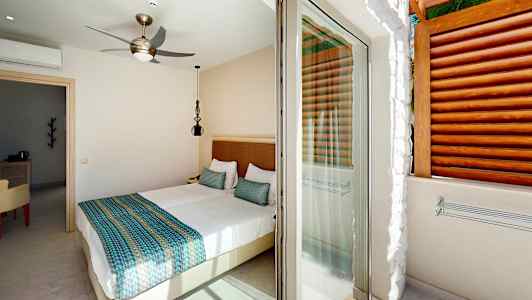 Vaalea makuuhuone, jossa on parivuode ja pääsy terassille. (Tekoälyn luoma teksti)