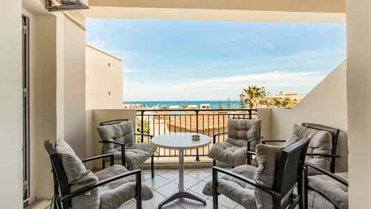 Terassi, jossa on neljä istumapaikkaa pöydän ympärillä, merinäköala taustalla. (Tekoälyn luoma teksti)