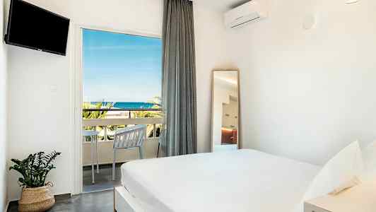 Valoisa makuuhuone, jossa on parisänky, seinällä televisio ja parveke merinäköalalla. (Tekoälyn luoma teksti)