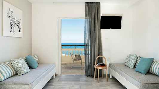 Modernisti sisustettu huone, jossa kaksi penkkiä, tyynyjä, pieni pöytä ja parveke merinäköalalla. (Tekoälyn luoma teksti)