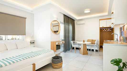 Moderni hotellihuoneen sisustus, jossa on sänky, ruokapöytä ja pieni keittiötila. (Tekoälyn luoma teksti)