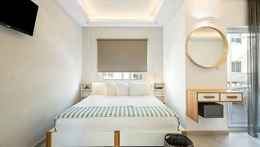 Modernisti sisustettu makuuhuone, jossa parivuode, seinälle kiinnitetty televisio ja pyöreä peili. (Tekoälyn luoma teksti)