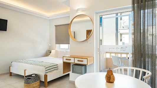 Nykyaikaisesti sisustettu hotellihuone, jossa sänky, peili ja parvekkeen ovi. (Tekoälyn luoma teksti)