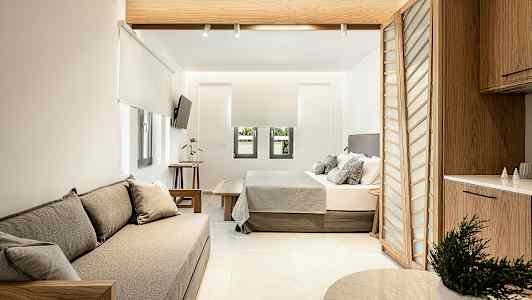 Nykyaikaisesti sisustettu hotellihuone, jossa on istuimet, sänky ja keittiötila. (Tekoälyn luoma teksti)