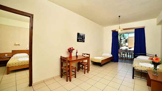 Hotellihuone, jossa on kolme sänkyä, ruokapöytä ja suuri ikkunasta avautuva näkymä. (Tekoälyn luoma teksti)