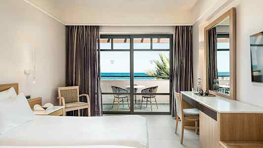 Hotellihuone, jossa on sänky, kirjoituspöytä ja parveke merinäköalalla. (Tekoälyn luoma teksti)