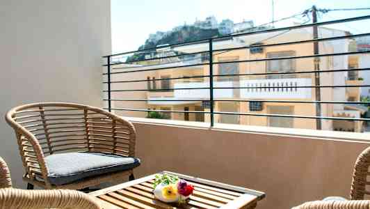 Terassi rottinkikalusteilla ja näkymä rakennuksiin taustalla. (Tekoälyn luoma teksti)