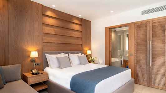 Hotellihuone, jossa on parivuode, seinällä puupaneelit ja liukuovi, joka johtaa kylpyhuoneeseen. (Tekoälyn luoma teksti)