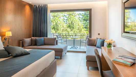 Moderni huone, jossa sänky, kirjoituspöytä ja istuinalue, näkymä patiolle ja vihreään maisemaan. (Tekoälyn luoma teksti)