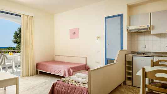 Hotellihuoneen sisätila, jossa kaksi yhden hengen vuodetta, pieni keittiö ja parveke näkymällä. (Tekoälyn luoma teksti)