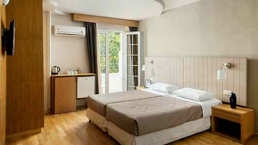 Hotellihuone, jossa on kaksi erillistä vuodetta, työpöytä, minibaarikaappi ja ranskalainen parveke. (Tekoälyn luoma teksti)