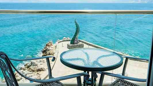 Näkymä terassilta merelle, etualalla kaksi tuolia ja pöytä. (Tekoälyn luoma teksti)