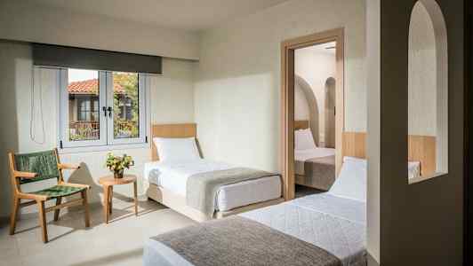 Hotellihuone, jossa on kaksi erillistä vuodetta, ikkuna ja ovi toiseen huoneeseen, jossa on yksi sänky. (Tekoälyn luoma teksti)