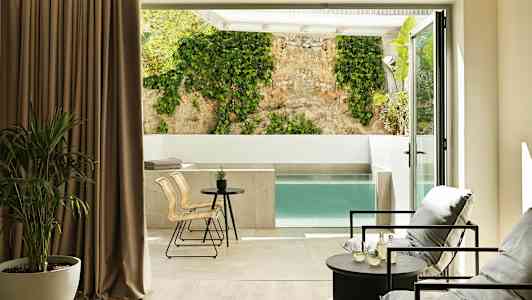 Moderni huone, jossa istuma-alue ja näkymä yksityiseen altaaseen ja seinään, jossa köynnöskasvi. (Tekoälyn luoma teksti)