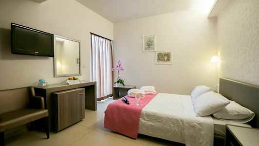 Hotellihuone, jossa on parivuode, yöpöytä ja kirjoituspöytä. (Tekoälyn luoma teksti)