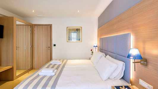 Hotellihuone, jossa on parivuode, puisia yksityiskohtia, sinisiä lamppuja ja peilikaappi. (Tekoälyn luoma teksti)