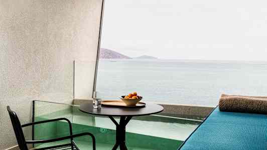 Terassi, jossa pöytä, tuoli ja istuinalue pienen altaan äärellä ja näkymä merelle. (Tekoälyn luoma teksti)