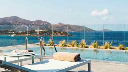 Ulkouima-allas, josta on näkymä merelle ja vuoristoon, ympäröity lasikaiteella ja aurinkotuoleilla. (Tekoälyn luoma teksti)