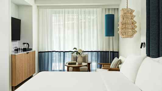 Hotellihuone, jossa parivuode, istuinalue ja TV. (Tekoälyn luoma teksti)