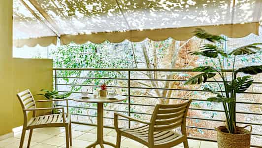 Terassi, jossa on pöytä ja kaksi tuolia lähellä kaidetta, koristeltuna kasveilla. (Tekoälyn luoma teksti)