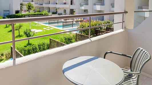 Näkymä parvekkeelta vehreään puutarhaan ja uima-allasalueelle. (Tekoälyn luoma teksti)