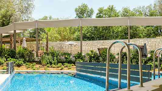 Ulkouima-allas ympäröivän vehreyden ja varjostettujen istumapaikkojen ympäröimänä. (Tekoälyn luoma teksti)