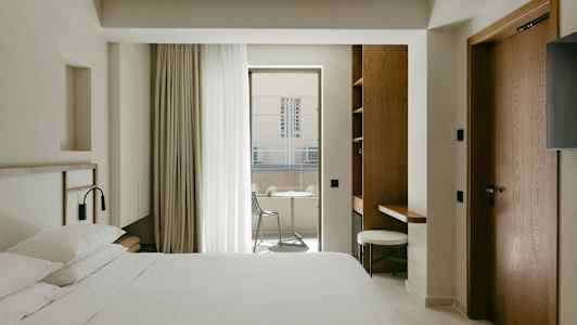 Hotellihuone, jossa on parivuode, työpöytä ja parveke ulkokalusteilla. (Tekoälyn luoma teksti)