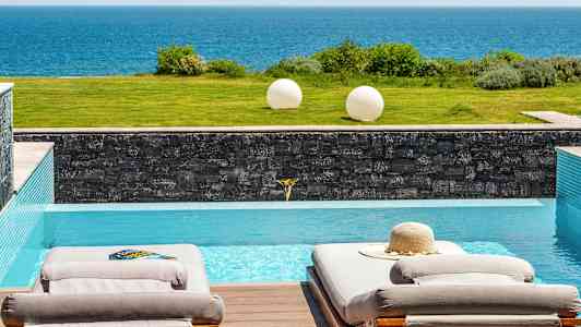 Kaksi aurinkotuolia altaalla, josta on näköala merelle. (Tekoälyn luoma teksti)