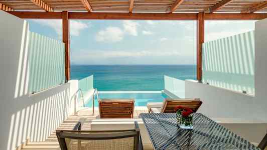 Näkymä terassilta, jossa on kaksi aurinkotuolia, pöytä ja yksityinen uima-allas, taustalla meri. (Tekoälyn luoma teksti)