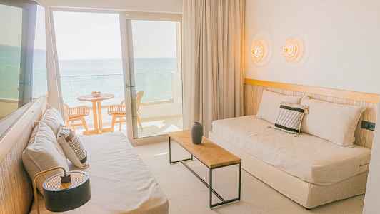 Hotellihuone, jossa on istuimia ja parveke merelle päin. (Tekoälyn luoma teksti)