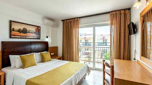 Hotellihuoneen sisätila, jossa sänky, kirjoituspöytä ja parveke. (Tekoälyn luoma teksti)