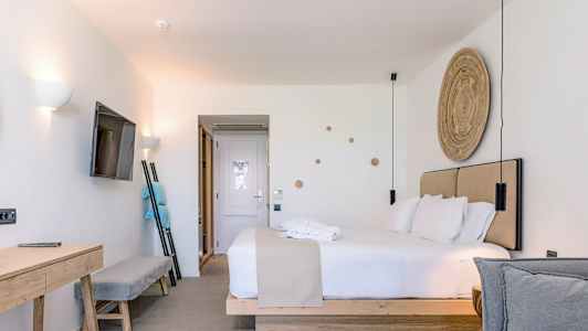 Nykyaikainen hotellihuone, jossa on parivuode, seinään kiinnitetty televisio ja kirjoituspöytä. (Tekoälyn luoma teksti)