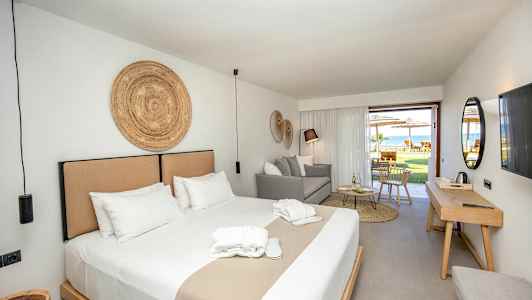 Hotellihuone, jossa on parivuode, istuma-alue ja uloskäynti kalustetulle terassille. (Tekoälyn luoma teksti)