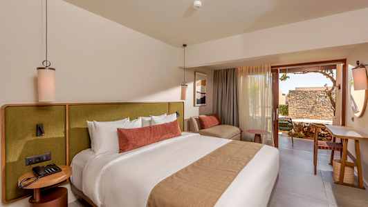 Moderni hotellihuone, jossa on suuri sänky, mukavat huonekalut ja terassi. (Tekoälyn luoma teksti)