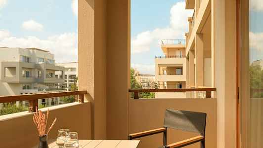 Parveke jossa pöytä, tuoli ja näkymä moderneja rakennuksia. (Tekoälyn luoma teksti)