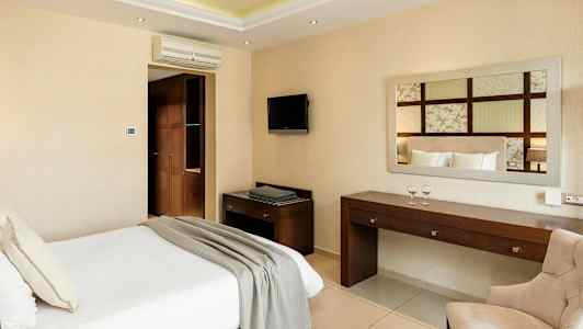 Hotellihuone, jossa sänky, työpöytä, tuoli ja seinätelevisio. (Tekoälyn luoma teksti)