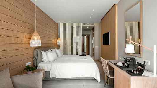 Valoisa ja moderni hotellihuone, jossa suuri parivuode, työpöytä ja koristeellinen marmoripaneeli seinällä. (Tekoälyn luoma teksti)