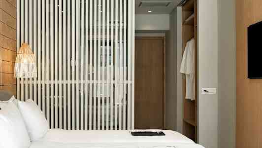 Hotellihuone, jossa sänky, puuseinä ja vaatekaappi. (Tekoälyn luoma teksti)