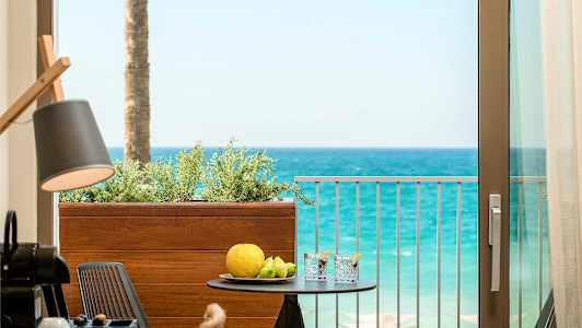 Näkymä parvekkeelta merelle pöydällä, jossa on hedelmiä ja juomia. (Tekoälyn luoma teksti)