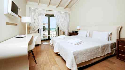 Hotellihuone, jossa on kaksi erillistä vuodetta, työpöytä ja parveke, jolta on näkymä. (Tekoälyn luoma teksti)