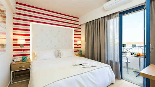 Hotellihuone, jossa sänky, yöpöytä ja avoin parvekkeen ovi. (Tekoälyn luoma teksti)