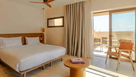 Huoneessa parivuode, pöytä ja tuoli, sekä lasiovi terassille. (Tekoälyn luoma teksti)